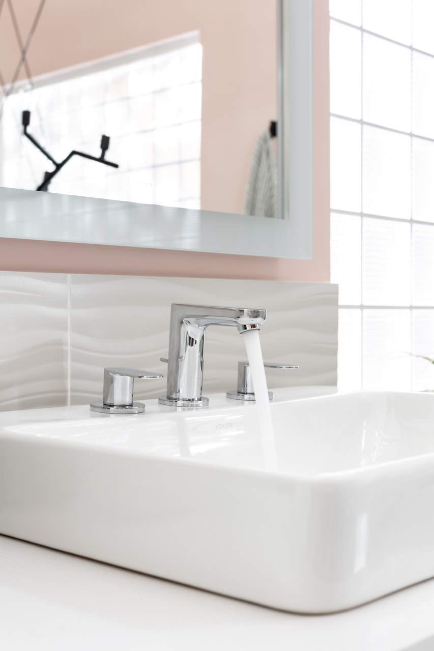Chrome widespread bathroom faucet with tall central spout and two side handles mounted on white sink basin.