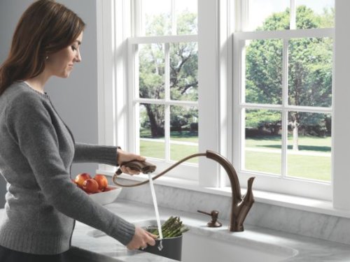 Venetian bronze soap dispenser mounted on kitchen sink countertop next to faucet.
