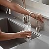 Satin nickel instant hot and cold water faucet with curved spout over sink basin.