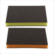 Two rectangular sanding sponges with dark gray abrasive surfaces and yellow and orange foam backing layers.