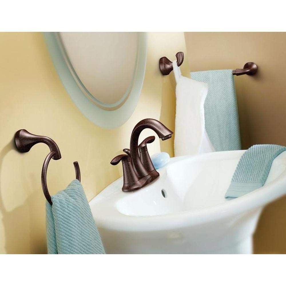 Oil rubbed bronze towel bar mounted on yellow bathroom wall above sink with folded towels.