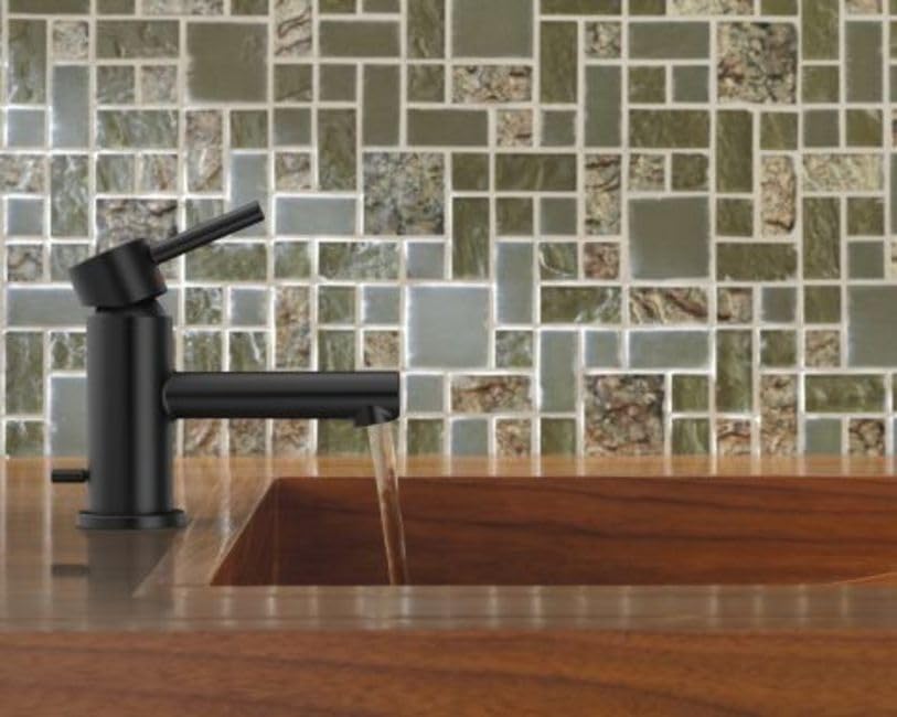 Brushed nickel single-handle bathroom faucet with low arc spout installed on wooden countertop with mosaic tile backsplash.