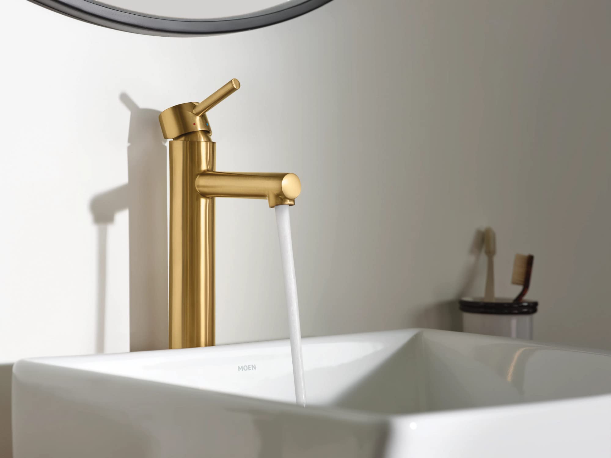 Brushed gold single-handle bathroom faucet with tall spout installed on white vessel sink.