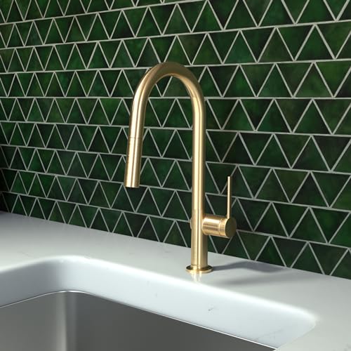 Brushed gold high-arc kitchen faucet with pull-down spray mounted on white countertop against green geometric tile backsplash