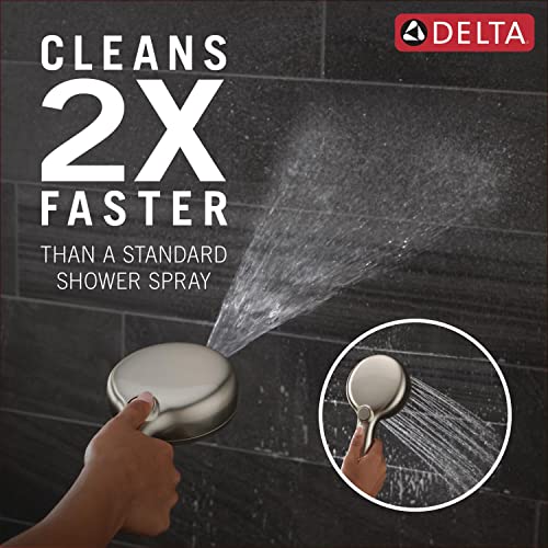 Brushed nickel hand shower with six spray settings being held against dark tile, demonstrating water stream spray pattern.