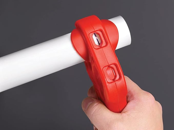 Red tubular cutter tool with two adjustment buttons gripped in hand around white pipe.
