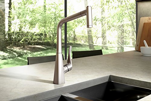 Stainless steel high-arc kitchen faucet with pull-down spray head over dark sink basin.