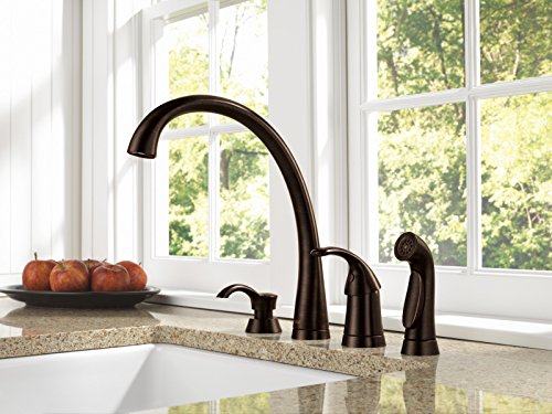 Venetian bronze kitchen faucet with curved spout and dual handles on countertop sink.