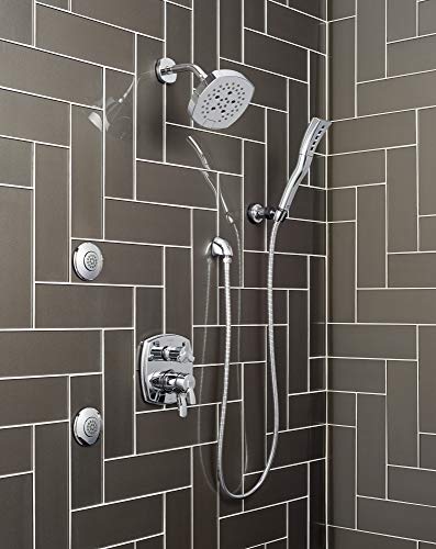 Polished chrome shower system with overhead and handheld showerheads, body jets, and integrated diverter valve on tile wall.