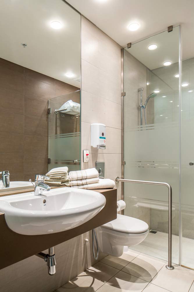 Chrome waste trap basin installed beneath white circular sink in modern bathroom.