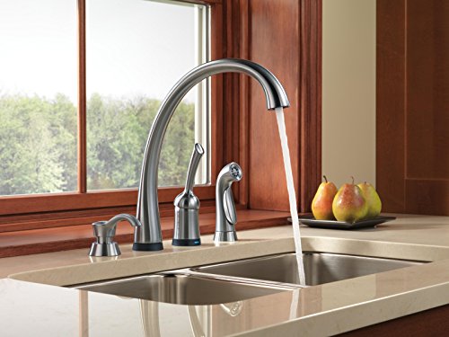 Arctic stainless steel kitchen faucet with curved spout and side spray mounted above double basin sink.