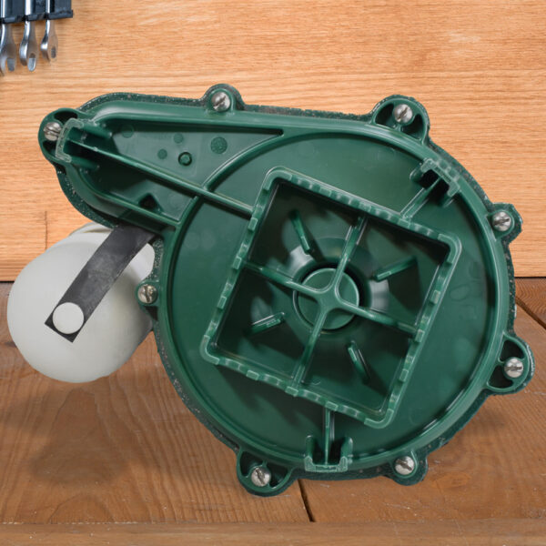 Green submersible sump pump with white float switch and power cord on wooden surface.