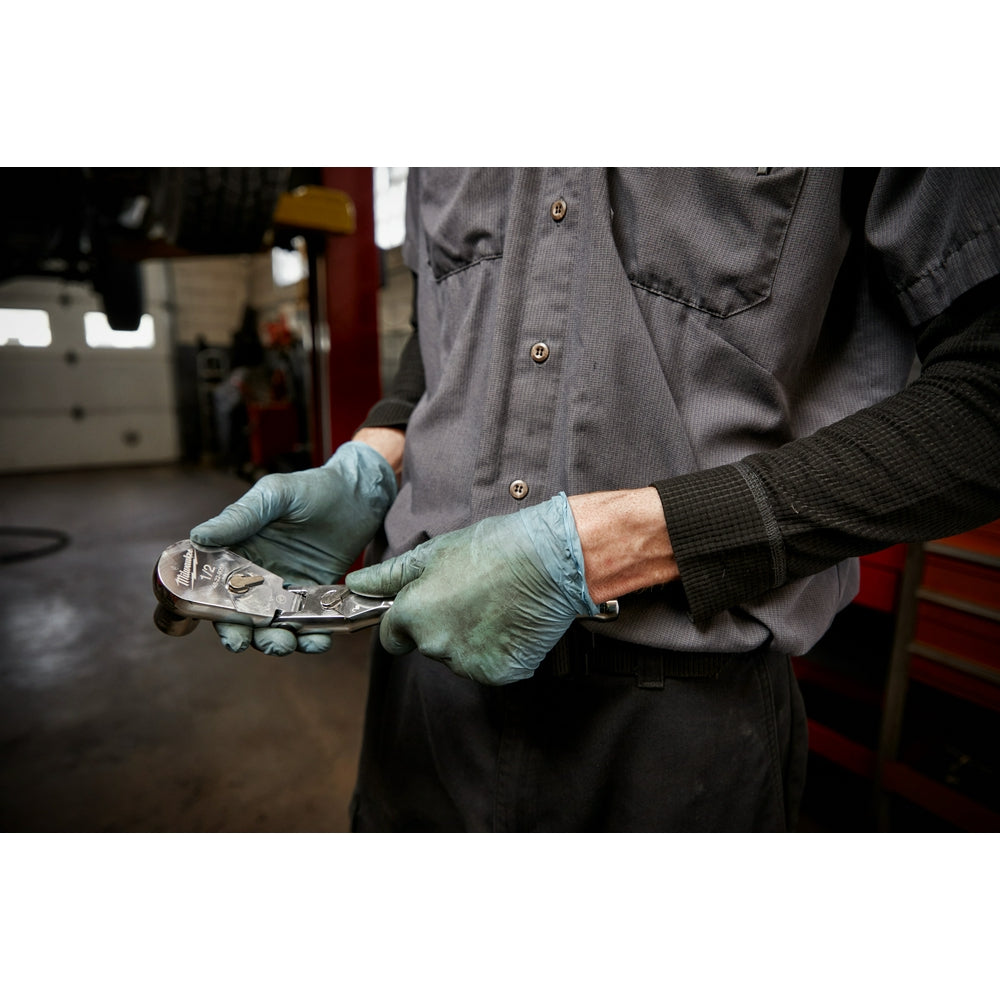 Mechanic in work gloves holding a 1/2" drive flex head ratchet wrench in a garage setting.