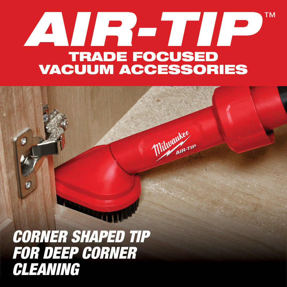 Red Milwaukee AIR-TIP rotating corner brush tool with black bristles cleaning a wooden corner and baseboard.