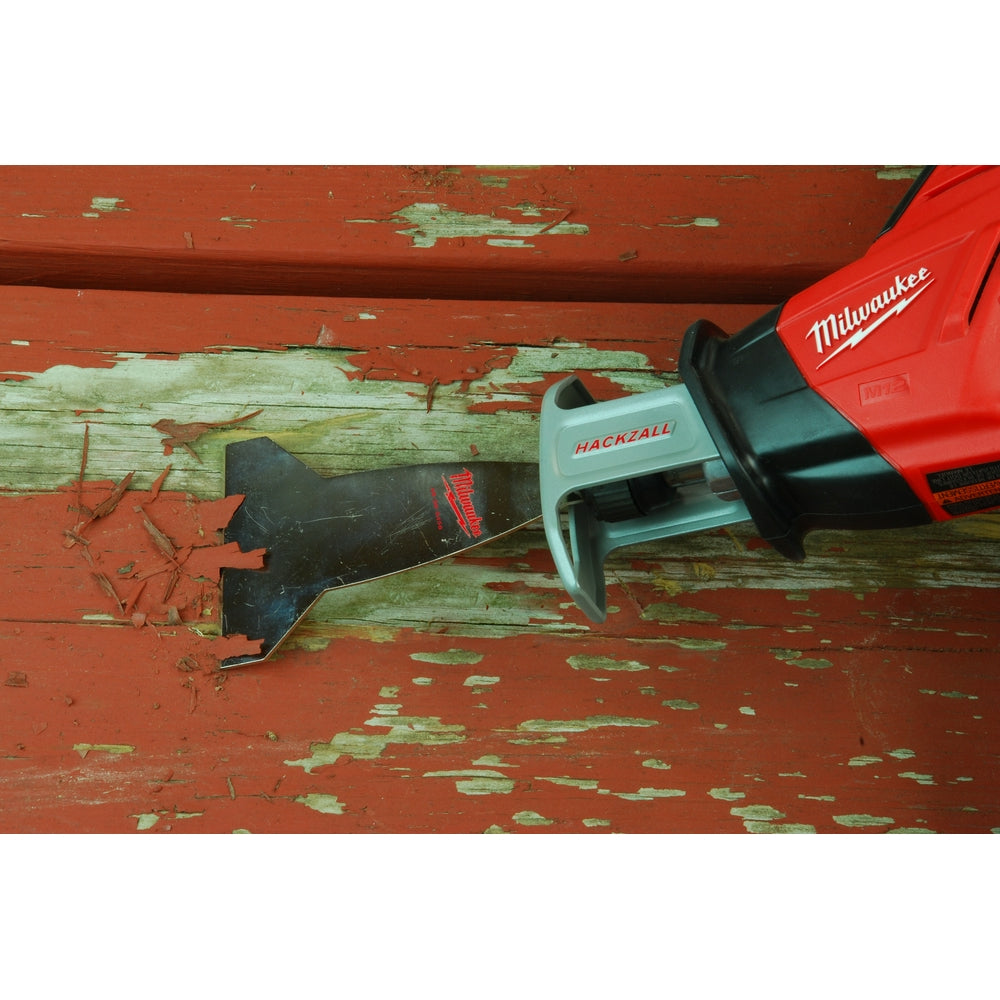 Milwaukee scraper blade with flat steel edge attached to red and black power tool, shown scraping paint from wooden surface.
