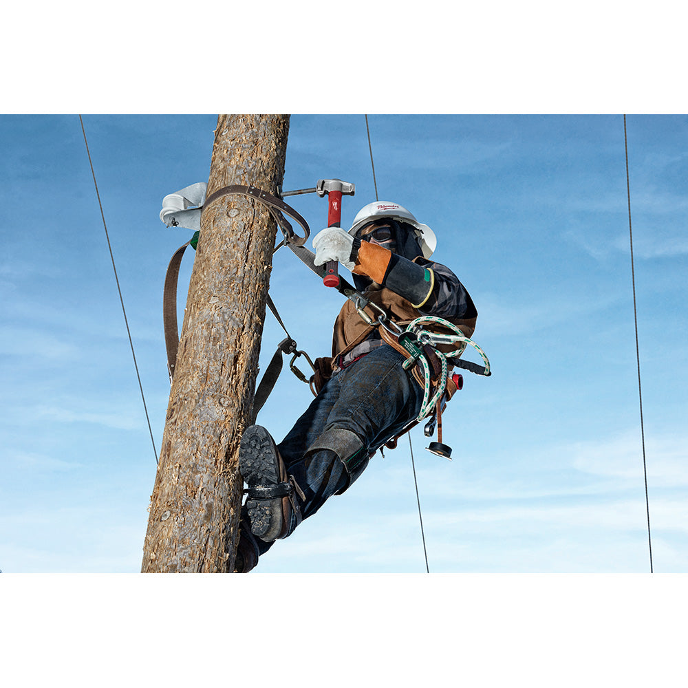 Lineman wearing safety gear climbing wooden utility pole with red hammer and tools in belt.