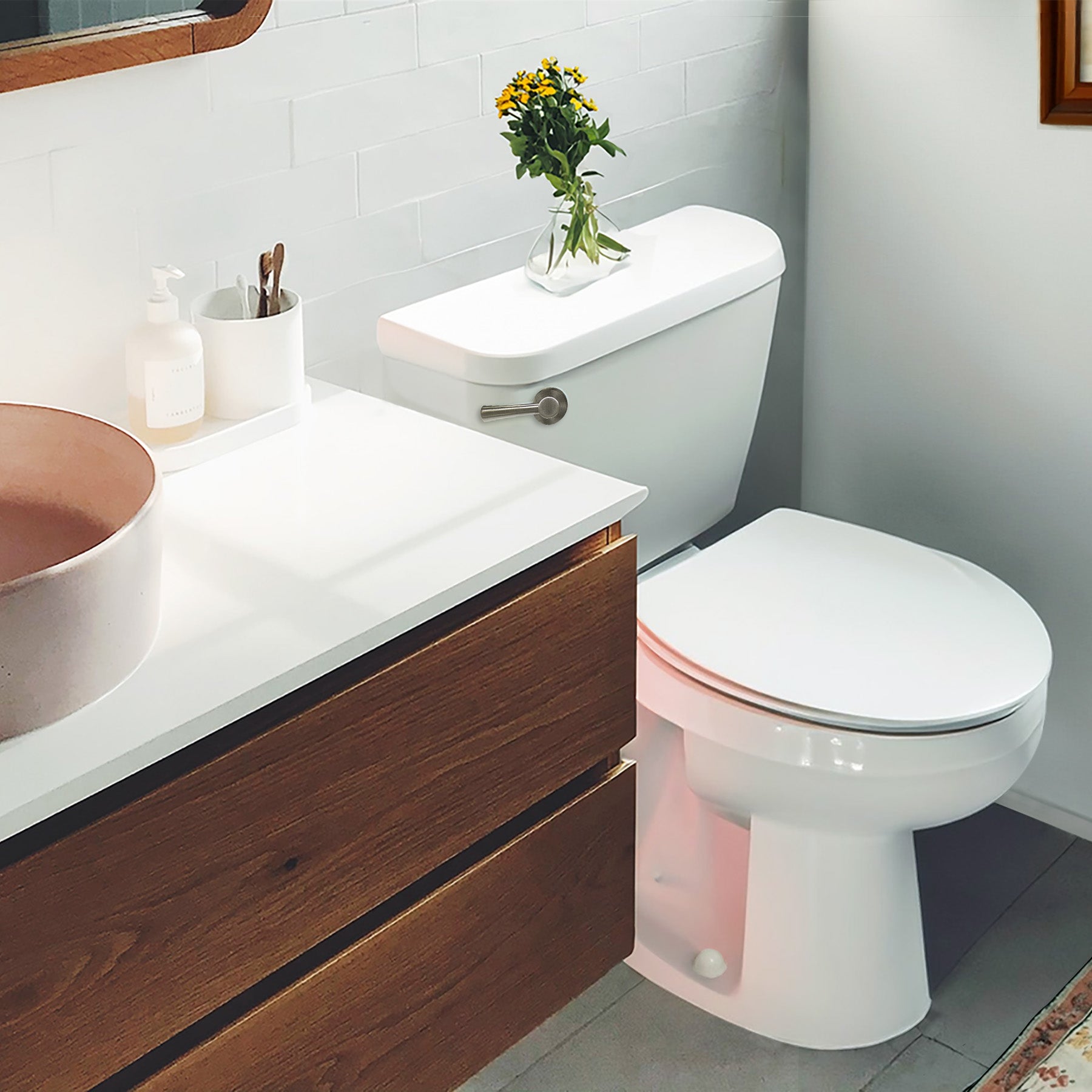 Brushed nickel lever handle mounted on white toilet tank in bathroom setting.