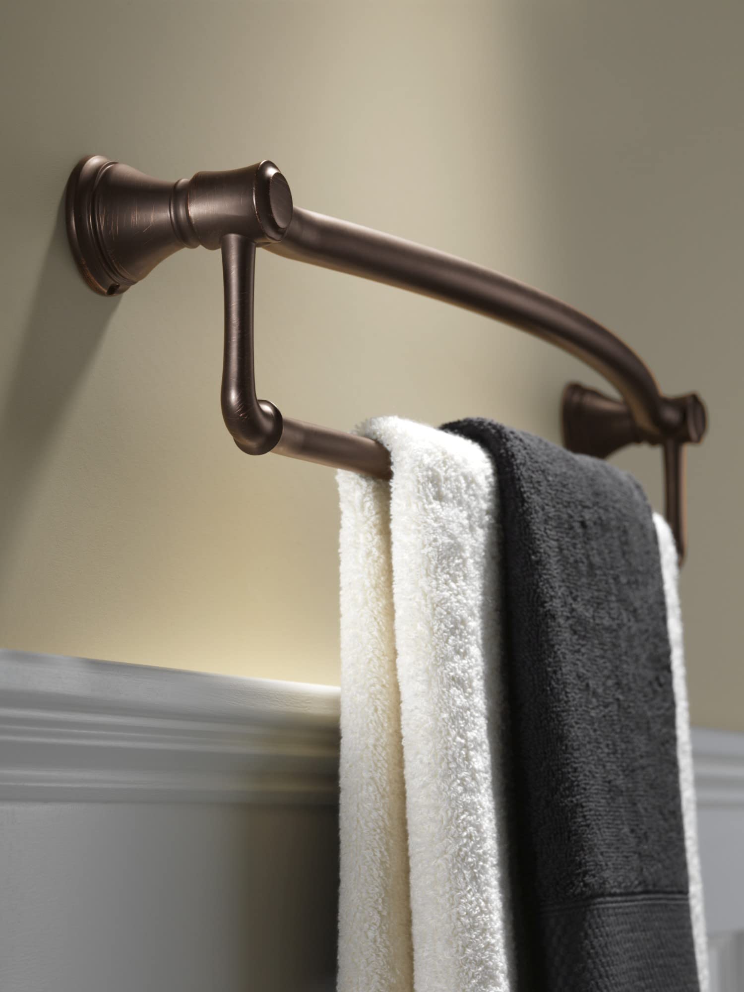 Stainless steel towel bar with assist handles mounted on wall with white and gray towels draped over bar.