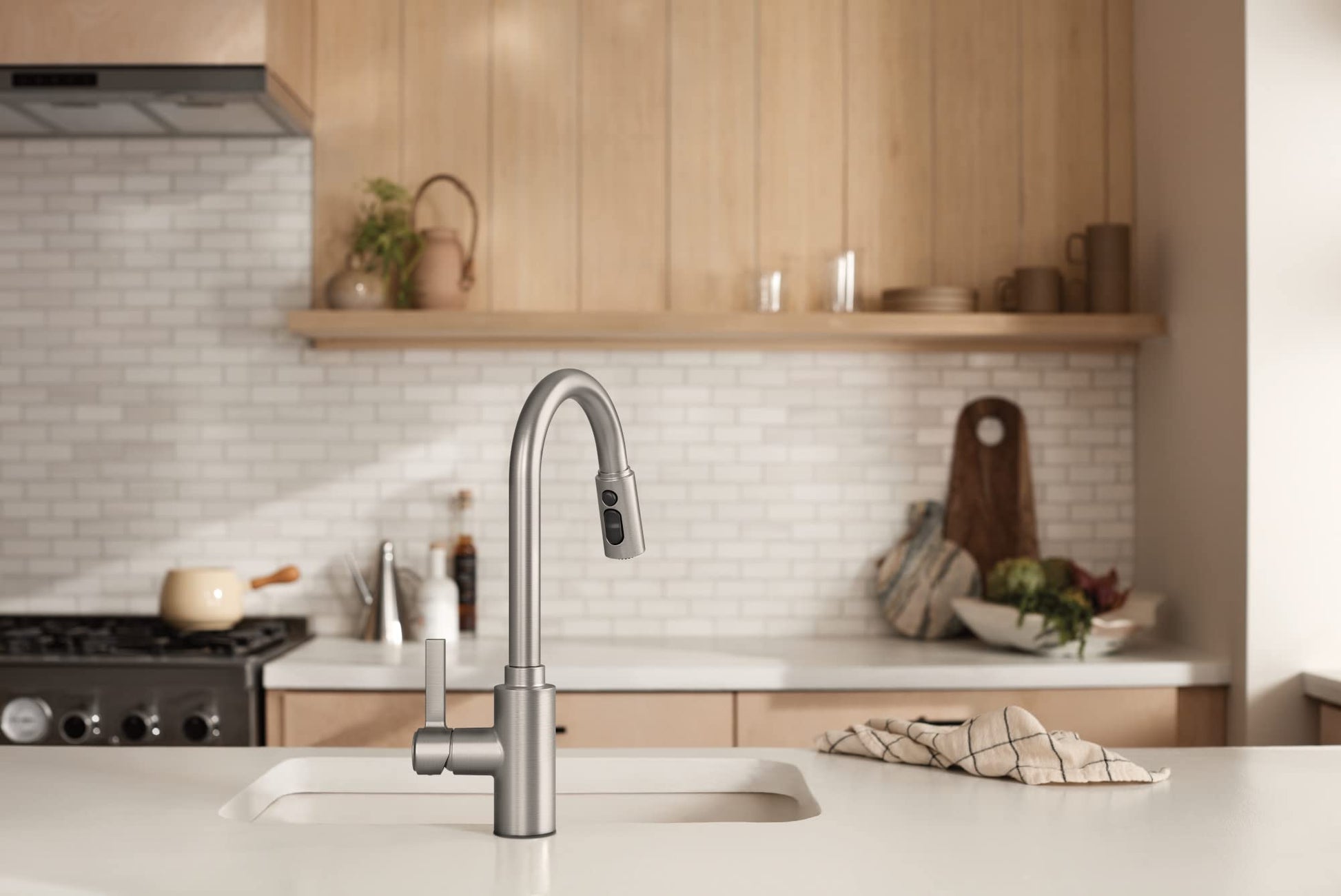 Stainless steel kitchen faucet with single handle and retractable pulldown sprayer mounted on white countertop.