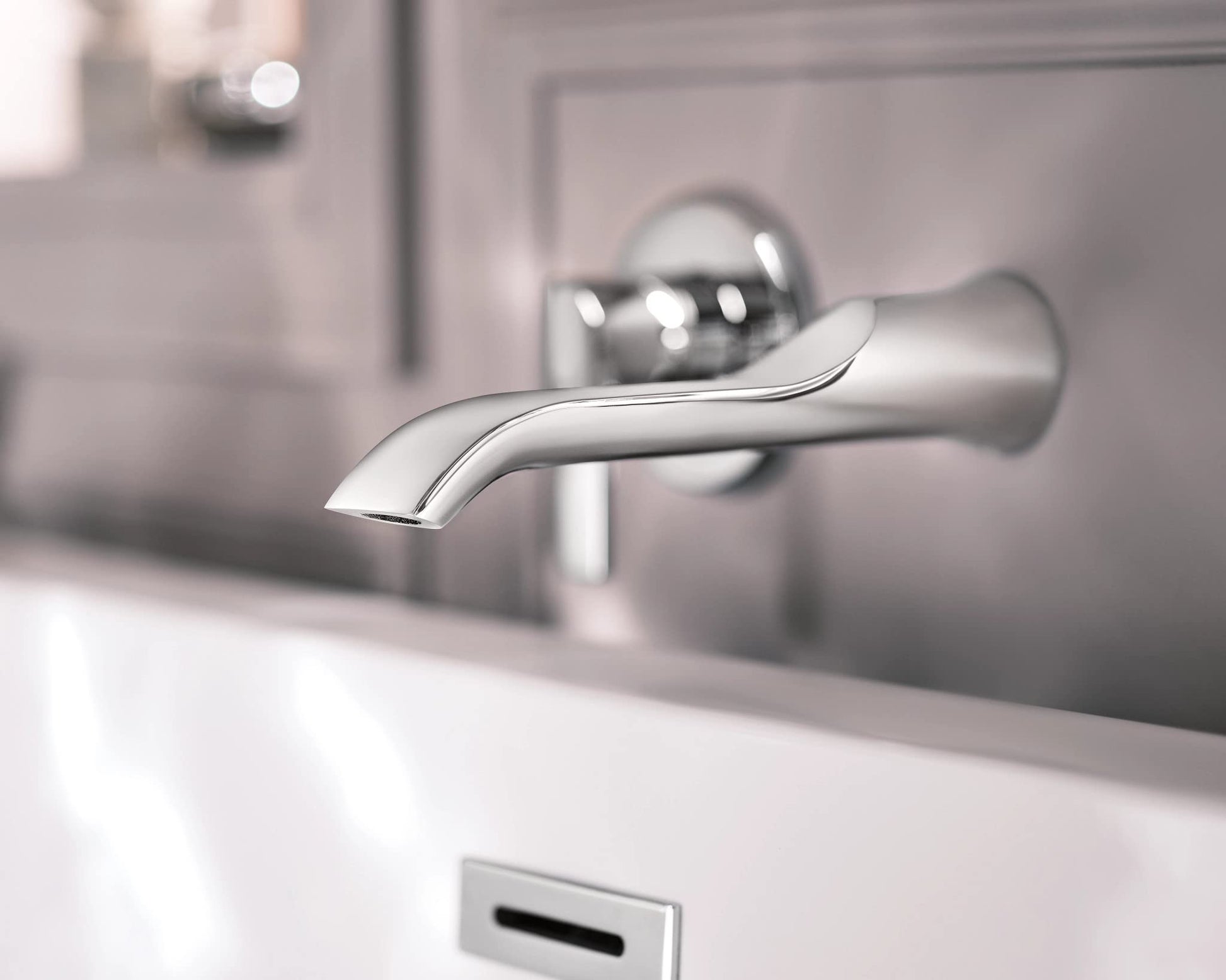 Chrome wall-mounted tub faucet with curved spout and single handle control mounted above white bathtub.