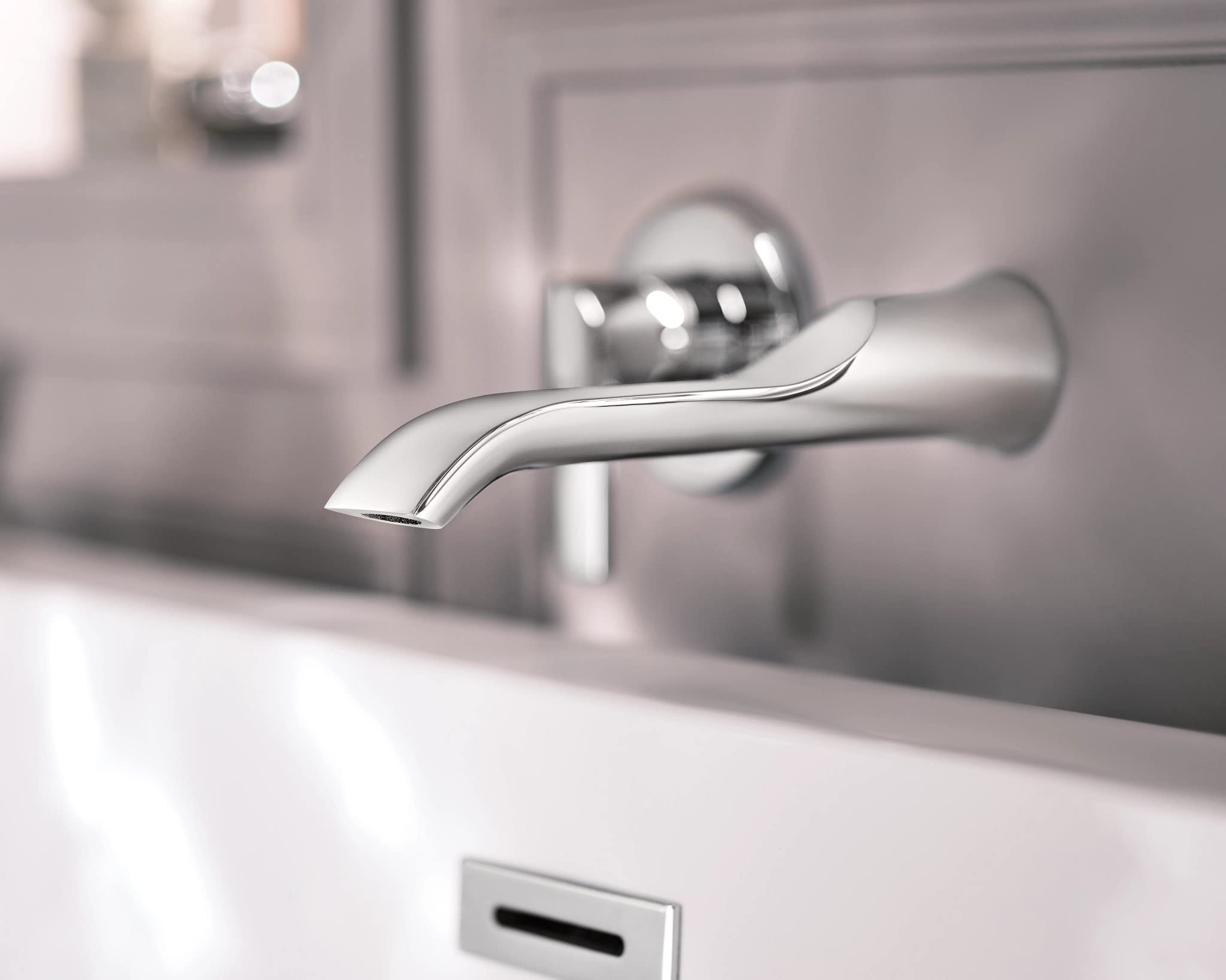 Chrome wall-mounted tub faucet with curved spout and single handle control mounted above white bathtub.