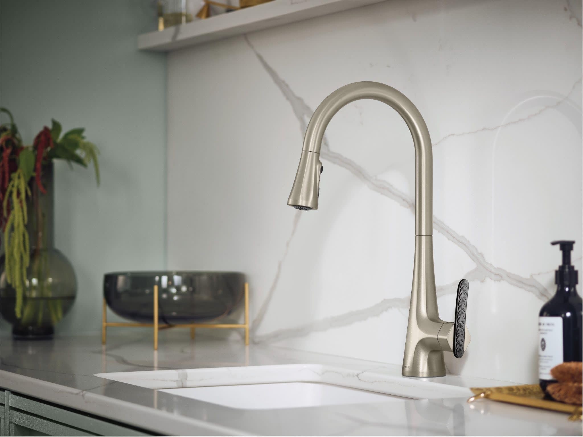 Stainless steel pulldown kitchen faucet with high arc spout and single handle installed above white sink.