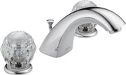 Chrome widespread bathroom faucet with two clear crystal knob handles and curved spout with pop-up drain.