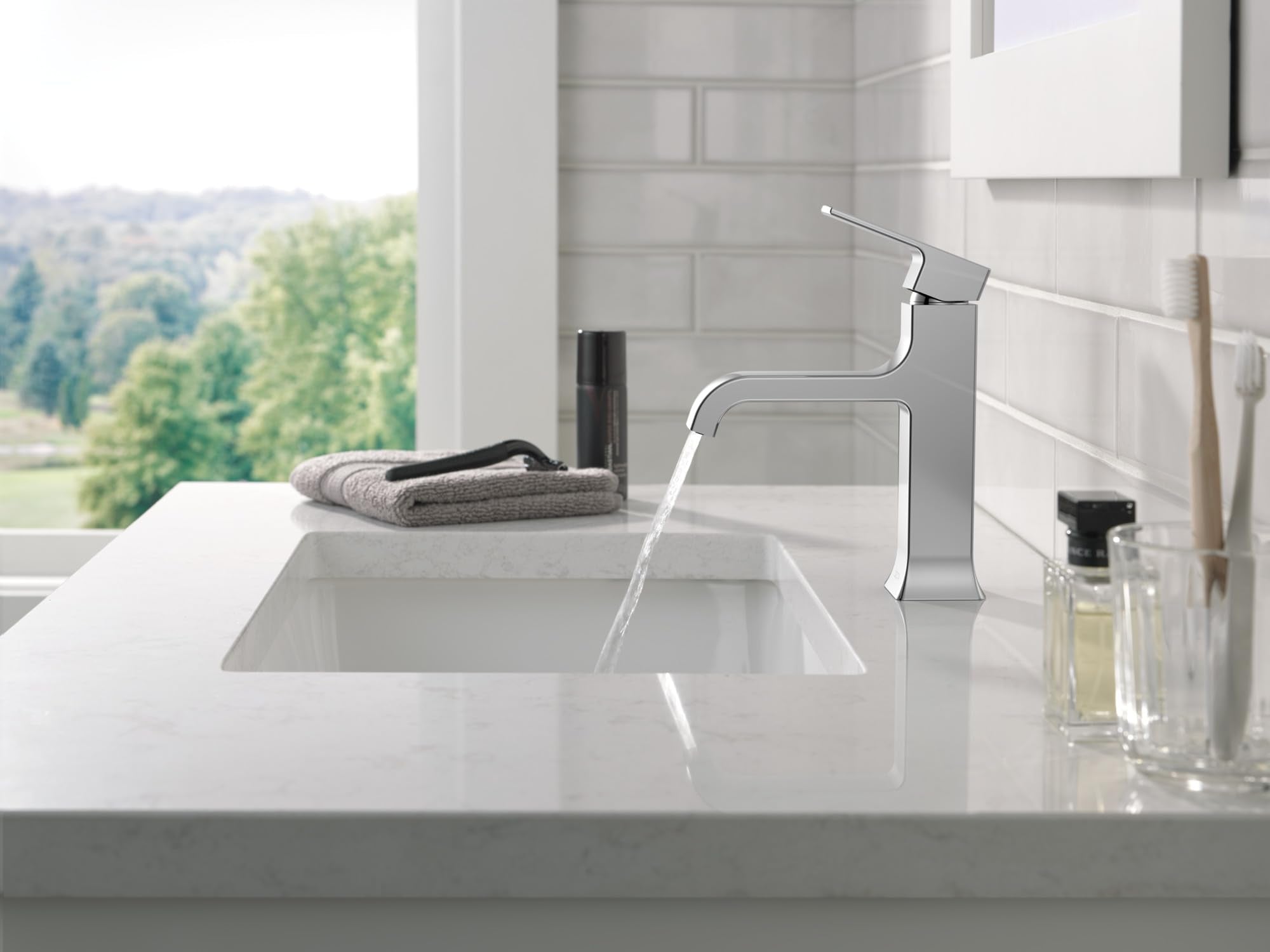 Chrome single-handle bathroom faucet with curved spout mounted on white sink counter.