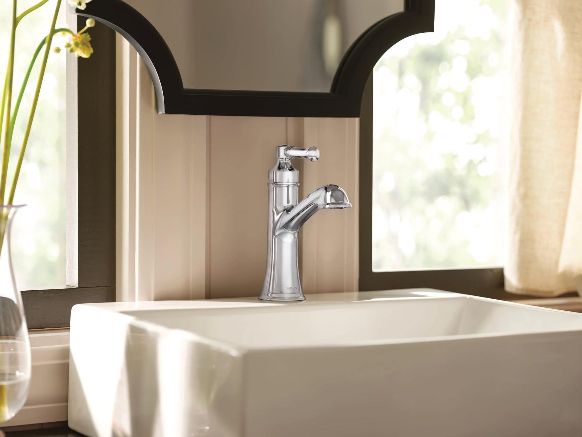 Chrome single-handle bathroom sink faucet with curved spout mounted on white vessel sink.