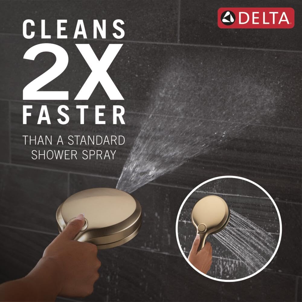 Champagne bronze round shower head with hand-held spray nozzle shown in use against dark tile background.