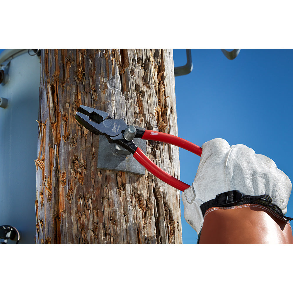 Black and red diagonal cutters with red handles cutting wire against a wooden pole.