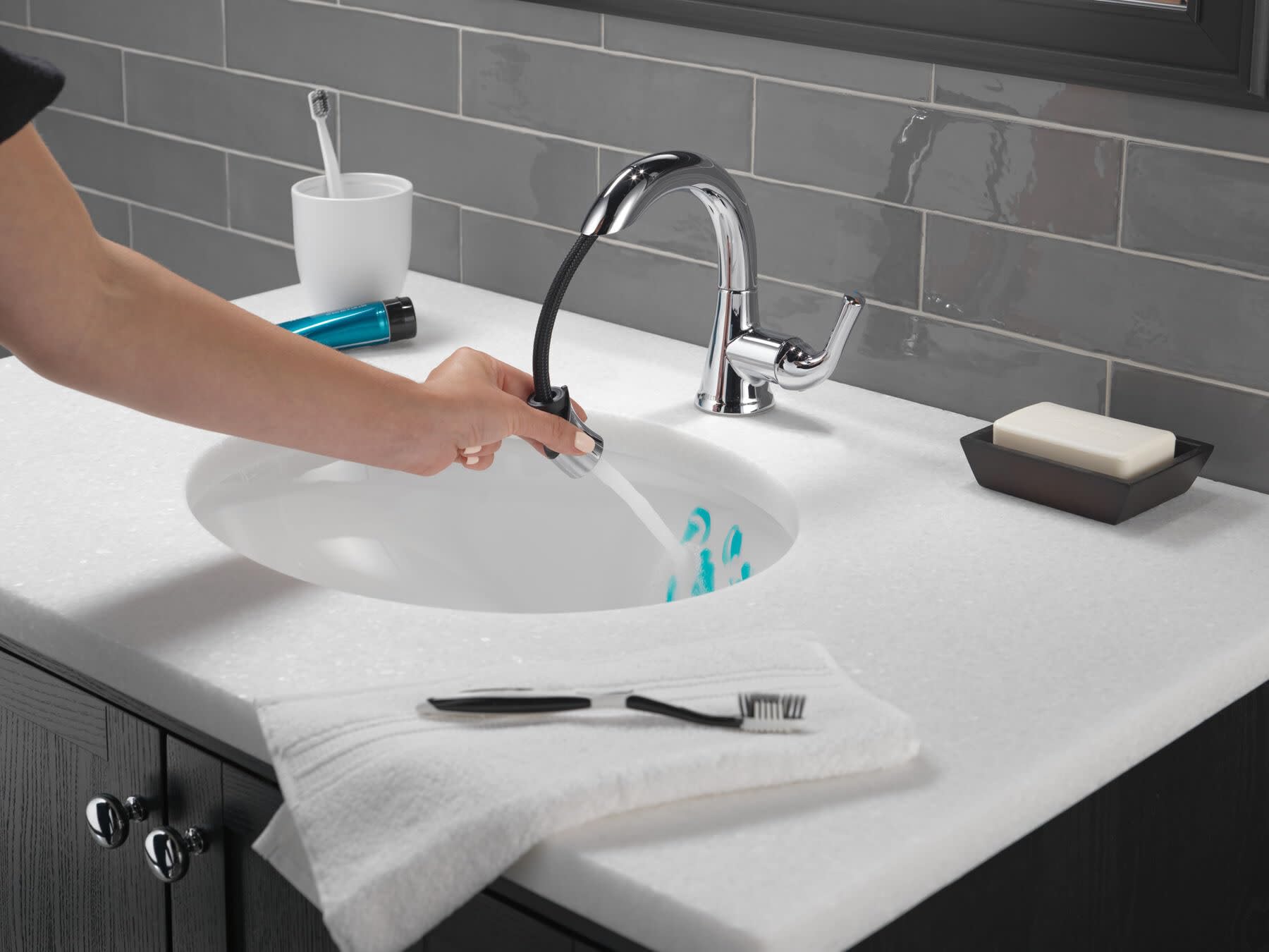 Chrome single-handle pull-down faucet with curved spout over white round bathroom sink.