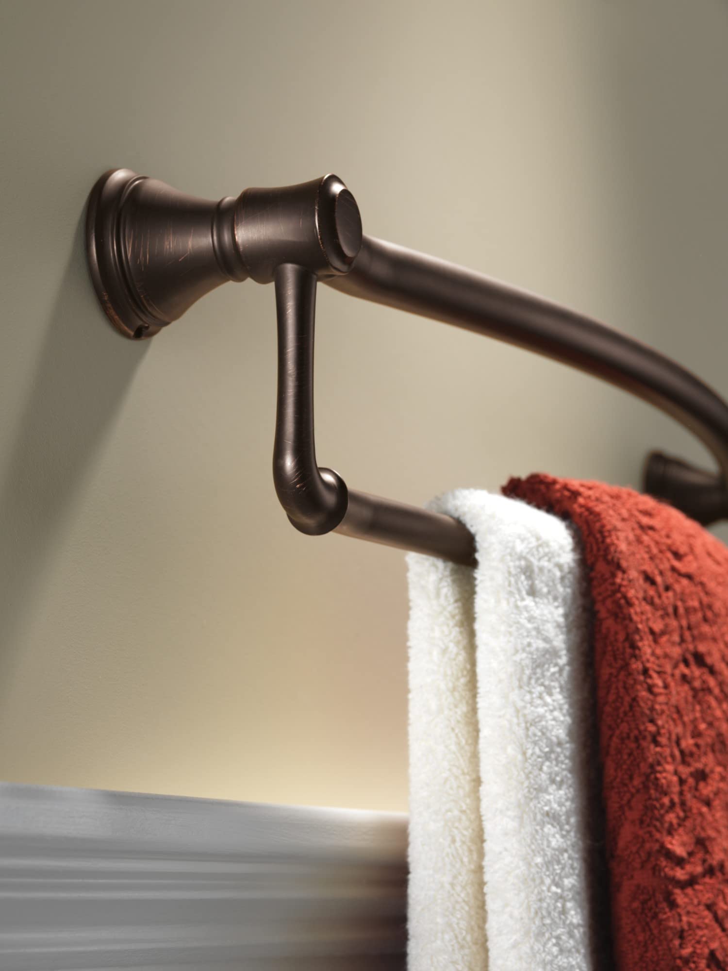 Oil-rubbed bronze towel bar with assist handle mounted to wall, holding white and rust-colored towels.