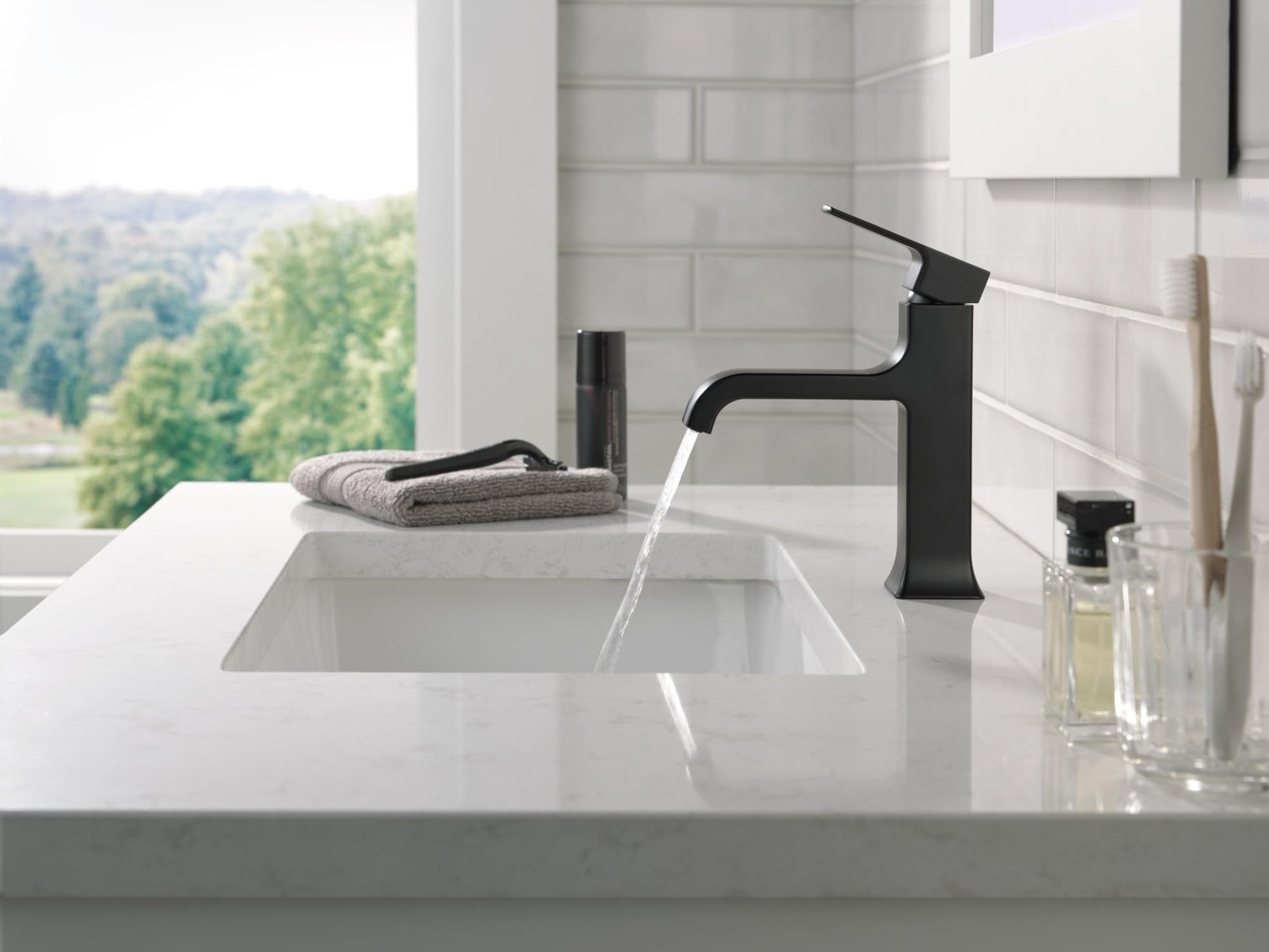 Matte black single-handle bathroom faucet with angled spout installed on white sink counter with running water.
