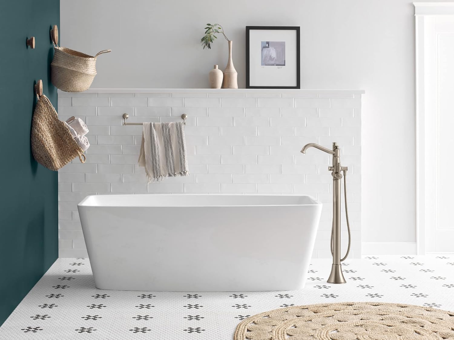 Chrome freestanding tub filler with single lever handle and attached handshower positioned next to white soaking tub.