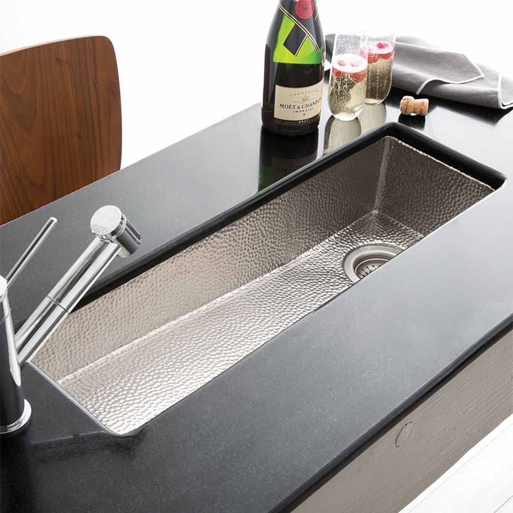 Hammered copper prep sink with single basin and textured interior, displayed with faucet and bar accessories.