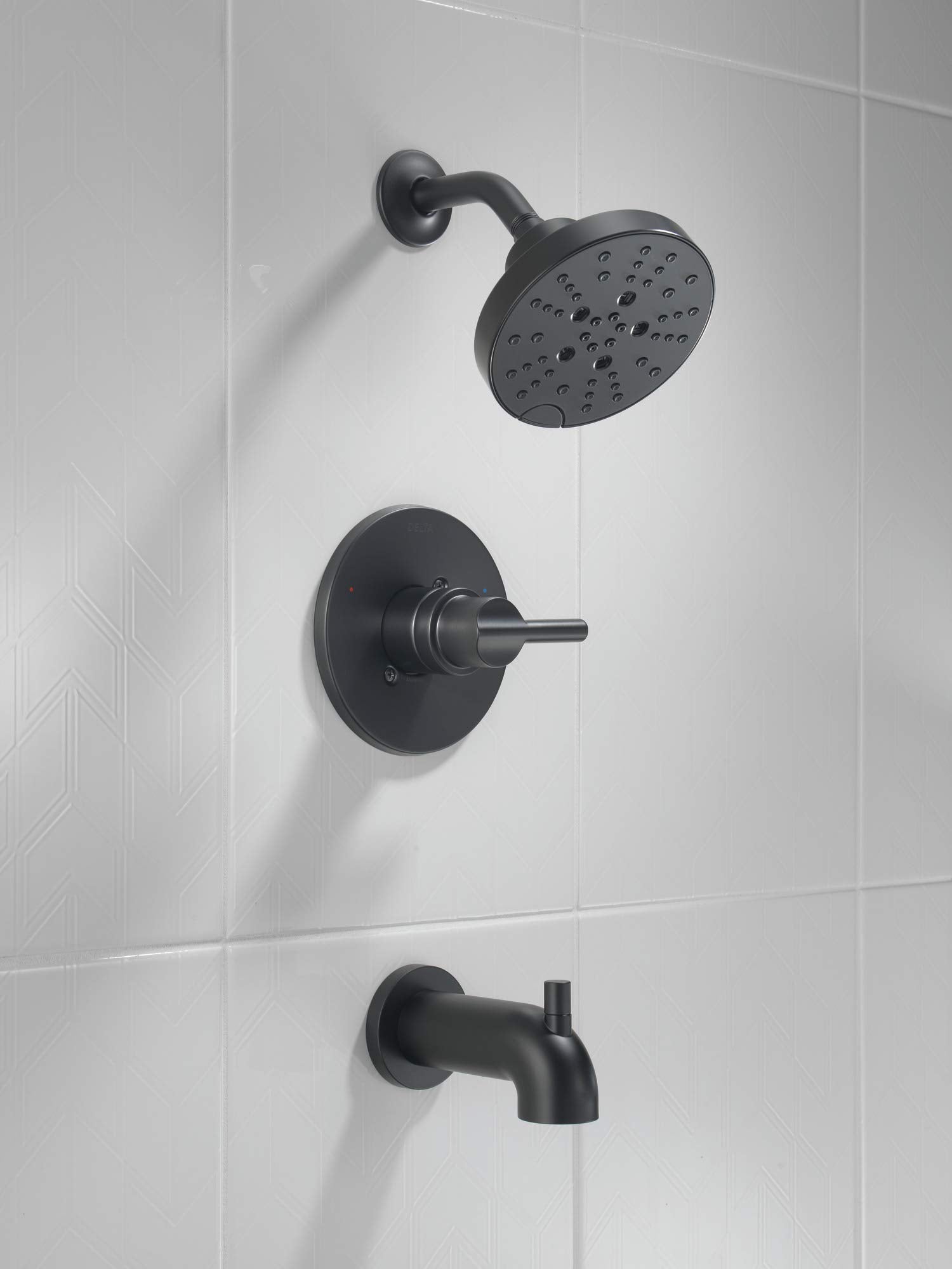 Matte black tub and shower faucet set with round showerhead, control valve, and tub spout mounted on white tile wall.