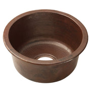 Hammered copper round bar sink with dark patina finish and single drain opening.
