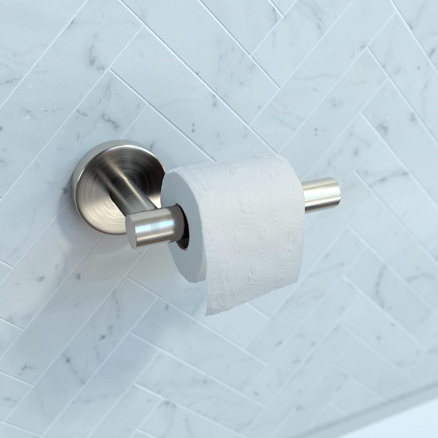 Brushed nickel toilet paper holder mounted on marble subway tile wall with white paper roll inserted.