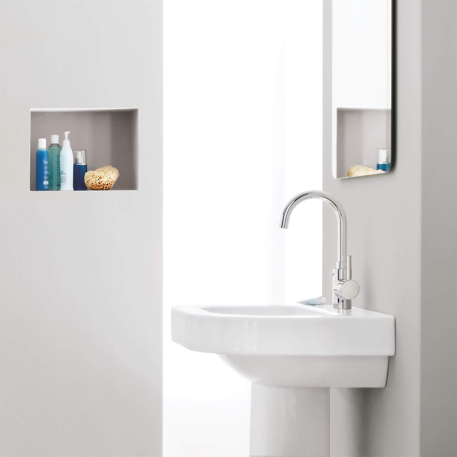 Chrome single-handle bathroom faucet with curved spout mounted on white pedestal sink.