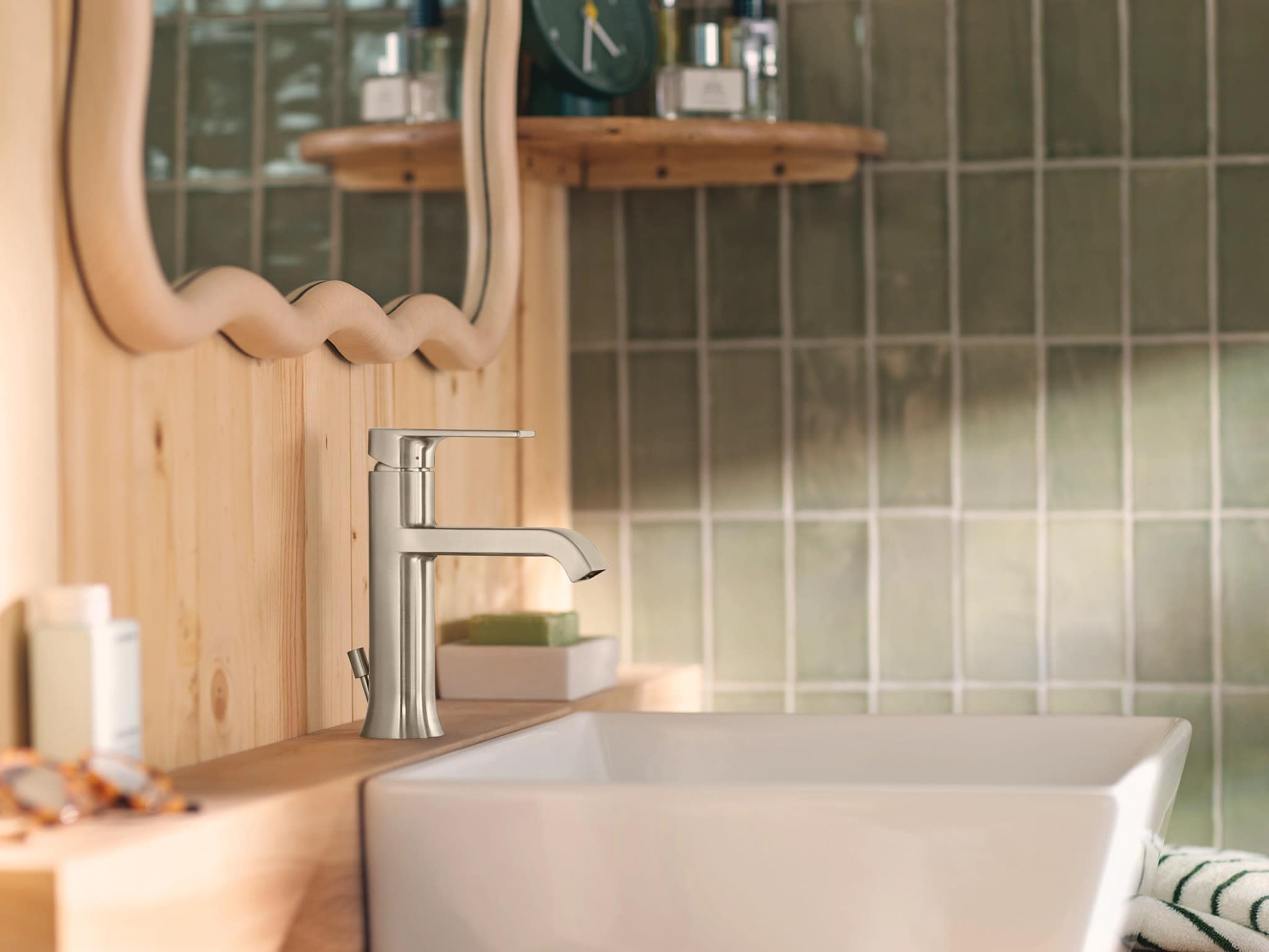 Brushed nickel single-handle bathroom faucet with curved spout mounted on white vessel sink.