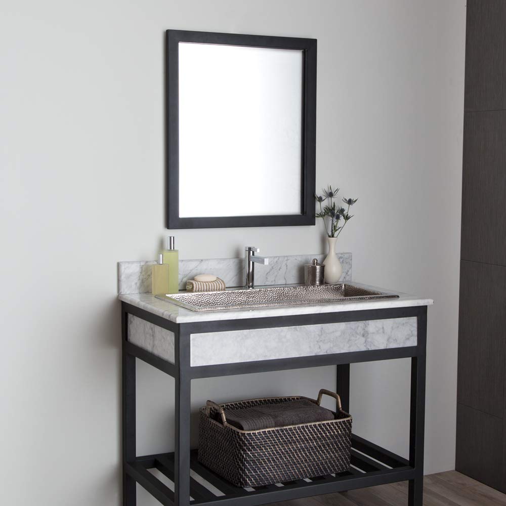 Black-framed rectangular mirror mounted above a marble and black bathroom vanity with sink.