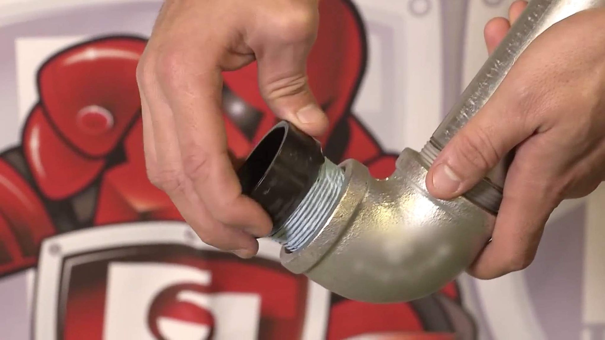 Thread sealant compound being applied to a metal pipe fitting with a brush applicator.