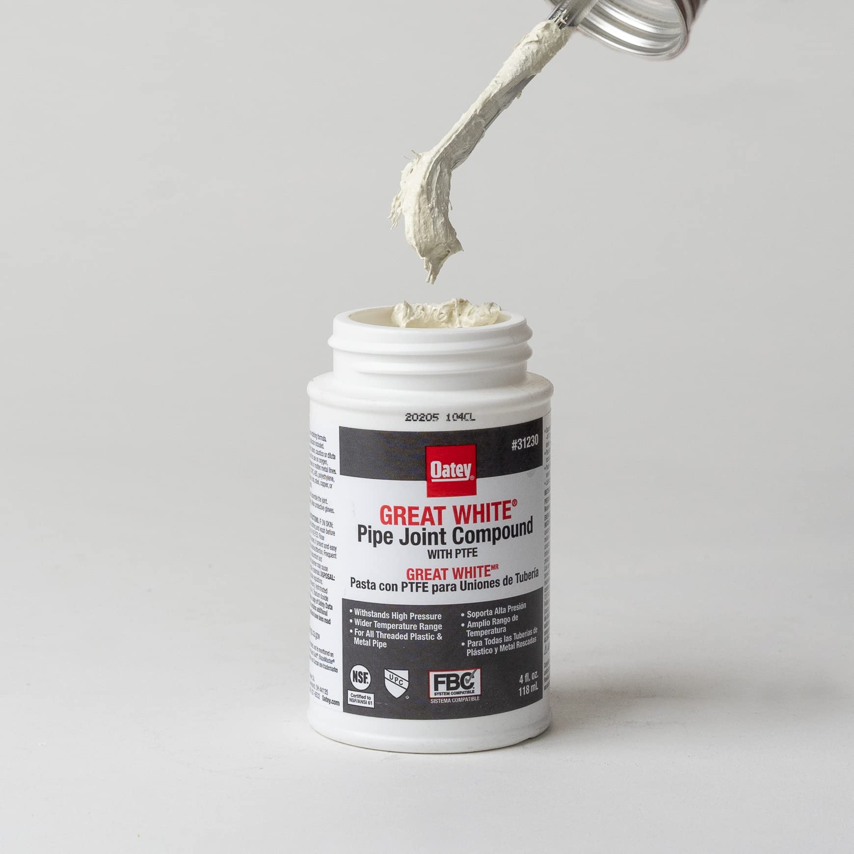 Oatey Great White pipe joint compound in 4 oz tube with applicator brush being dispensed from container.