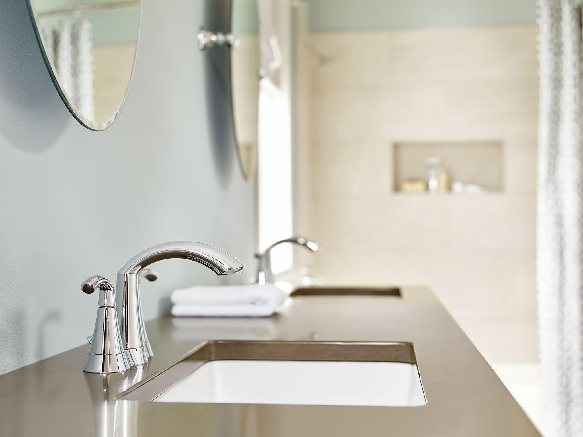 Chrome bathroom faucet with high arc spout and two lever handles mounted on vanity sink.