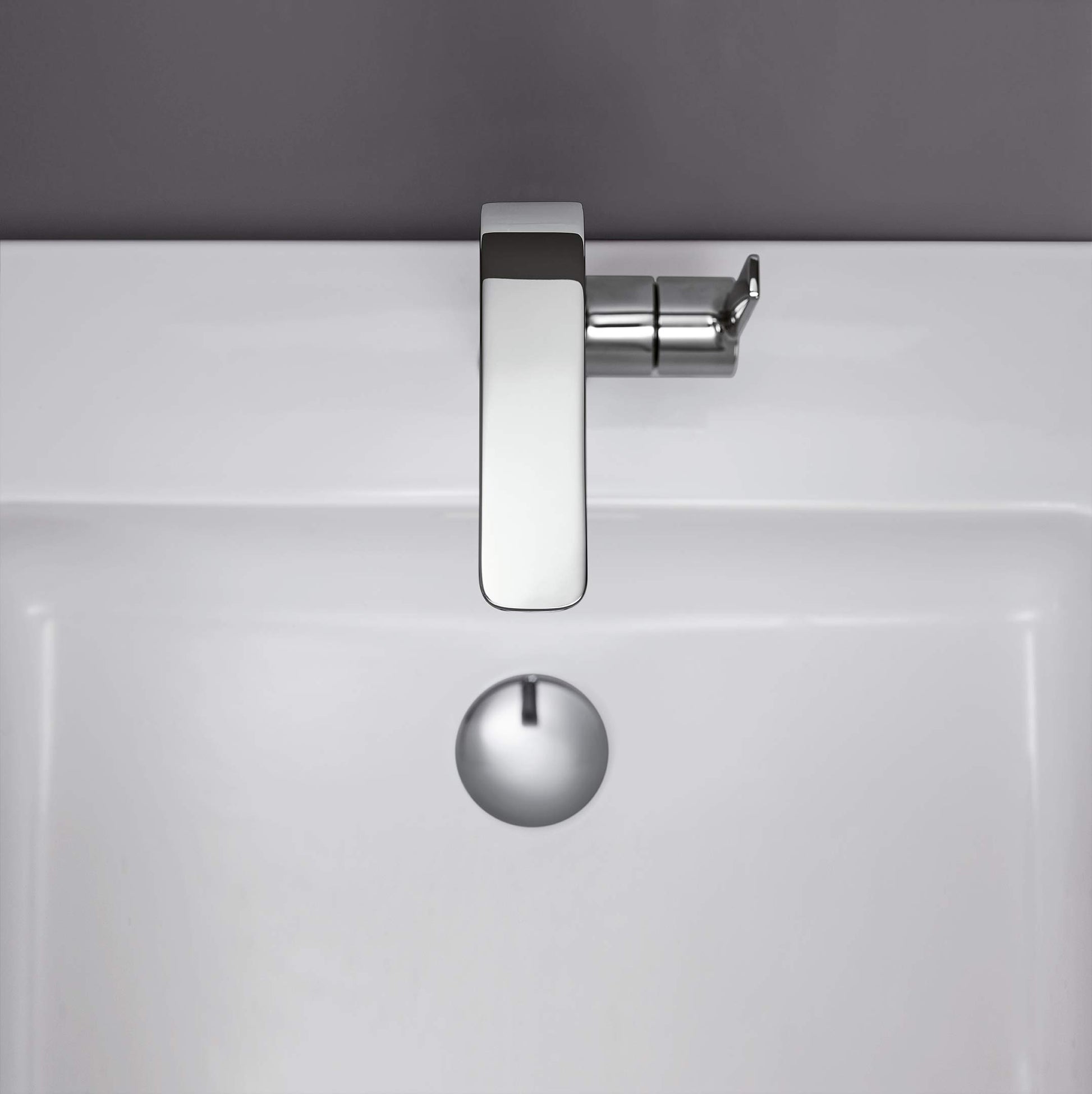 Chrome single-handle bathroom faucet with elongated spout mounted on white sink basin.