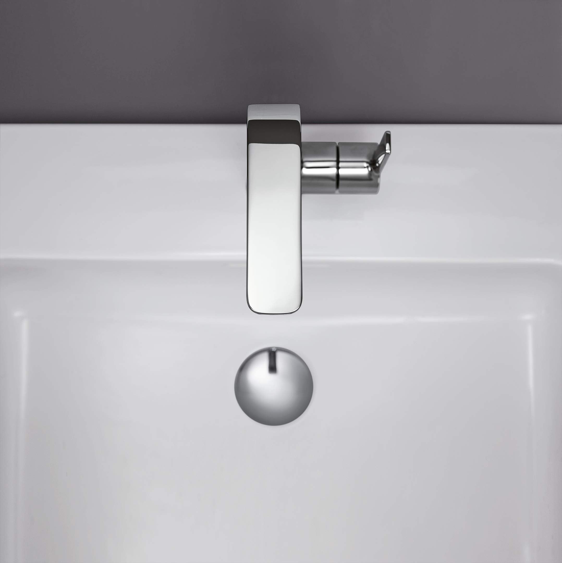Chrome single-handle bathroom faucet with elongated spout mounted on white sink basin.