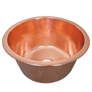 Polished copper round bar sink with hammered interior finish and single drain hole.