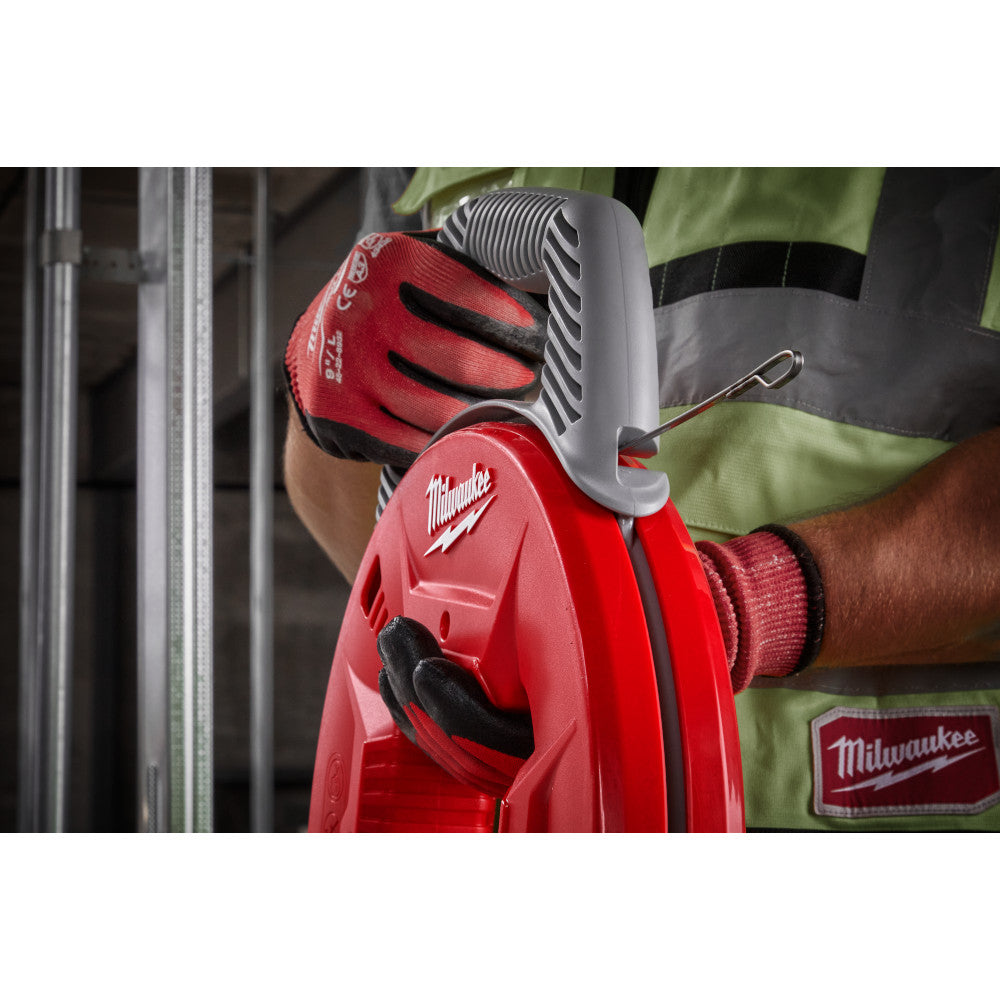 Milwaukee stainless steel fish tape with red reel case held by gloved hands during electrical work installation.