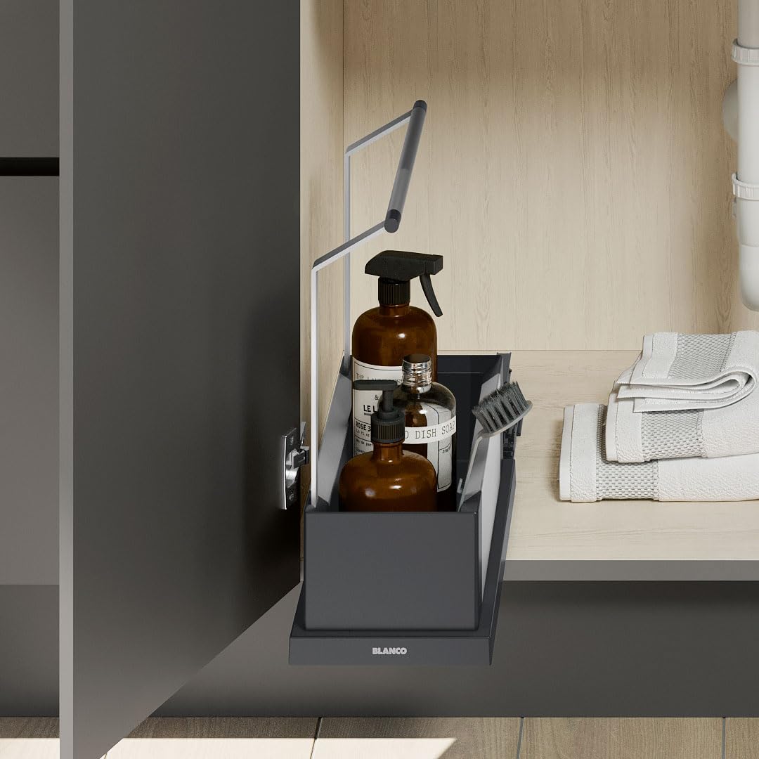 Black storage caddy with pivoting handle holding two amber glass bottles and cleaning brush on countertop.